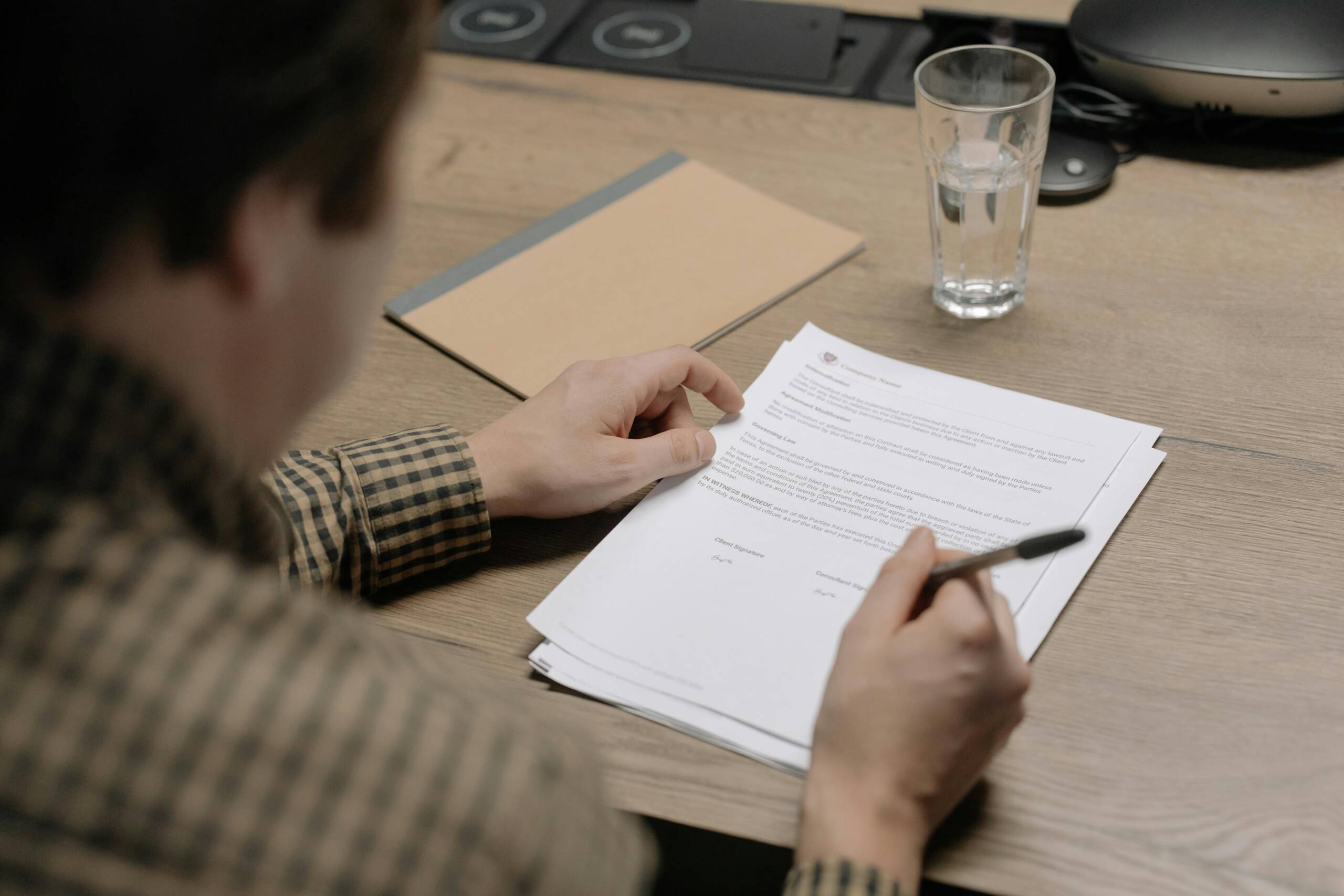 Person reviewing and signing a document at a desk